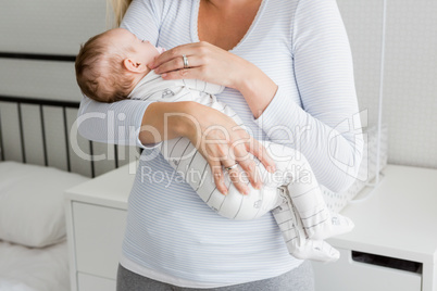 Mid-section of mother holding her baby boy