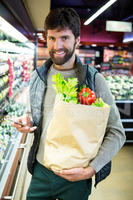 Portrait of smiling man holding a grocery bag in organic section