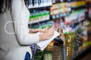 Woman writing on notepad while shopping in grocery section