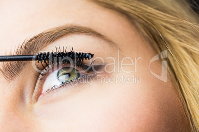 Beautiful woman applying mascara on eyelashes