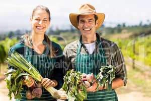 Portrait of happy farmer couple holding leafy vegetables