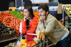 Bored couple with shopping trolley in organic section