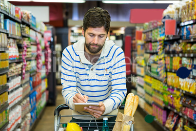 Man writing on notepad while shopping in grocery section