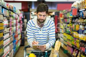 Man writing on notepad while shopping in grocery section