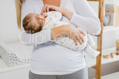Mid-section of mother holding her baby boy