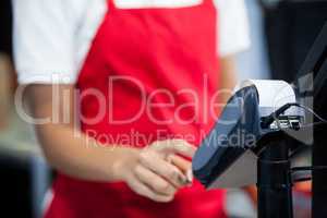 Female staff using credit card terminal at cash counter