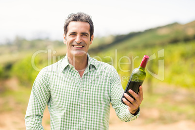 Smiling vintner holding bottle of wine