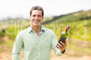 Smiling vintner holding bottle of wine