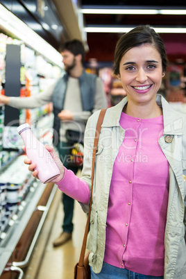 Woman holding milk bottle and smiling