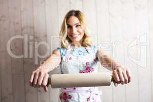 Woman in apron holding a rolling pin against texture background