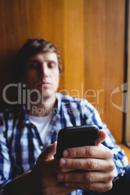 Student using mobile phone near window