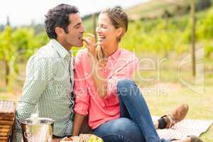 Woman feeding man with grape