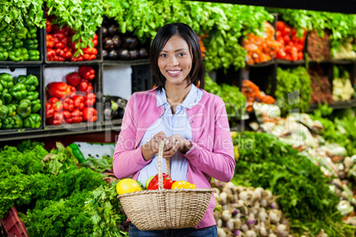 Smiling woman holding fruits and vegetables in basket