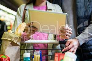 Couple using digital tablet while shopping