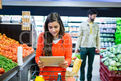 Woman using digital tablet while shopping