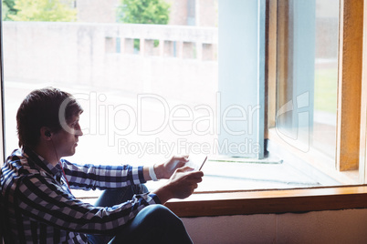 Student using digital tablet near window