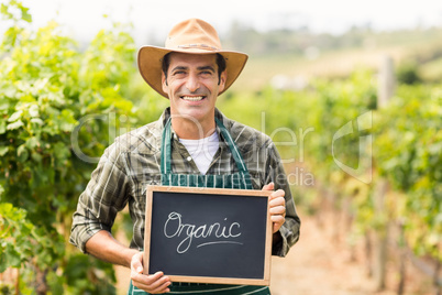 Portrait of smiling farmer holding an organic sign