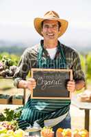 Portrait of smiling farmer holding an organic sign