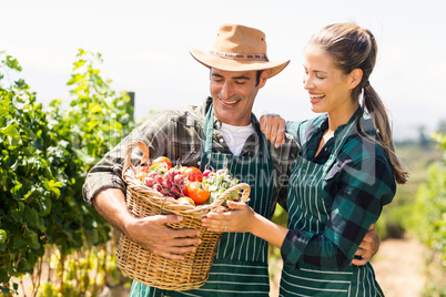 Happy farmer couple holding a basket of vegetables