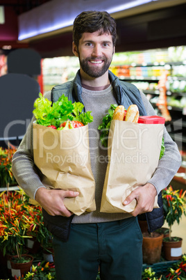 Portrait of smiling man holding a grocery bag in organic section