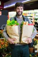 Portrait of smiling man holding a grocery bag in organic section