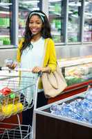 Woman looking at bottle of water at grocery section in supermarket