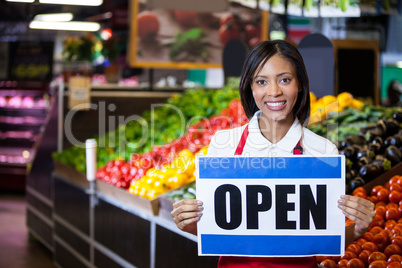 Smiling female staff holding open signboard