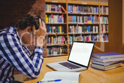 Depressed student sitting in library with laptop