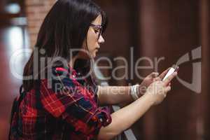 Female student using mobile phone in corridor