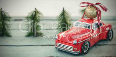 Toy car carrying christmas bauble ball on wooden plank