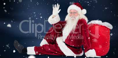 Composite image of santa sits leaned on his bag and waves