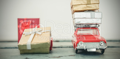 Toy car carrying christmas present on wooden plank