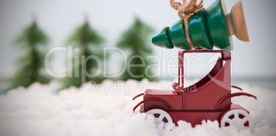 Toy car carrying christmas tree on fake snow