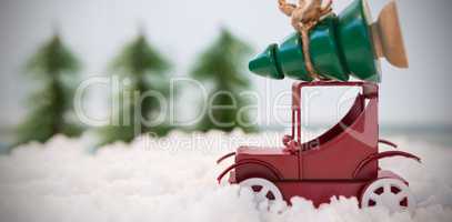 Toy car carrying christmas tree on fake snow