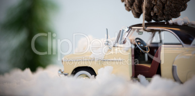 Toy car carrying pine cone on fake snow