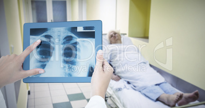 Composite image of doctor looking at xray on tablet