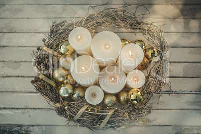 Candles and bauble ball in nest basket on wooden plank