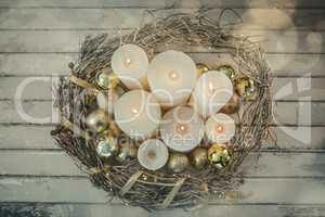 Candles and bauble ball in nest basket on wooden plank