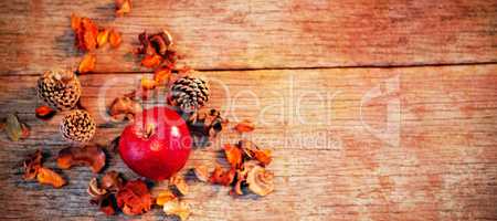 Apple and pine cone on wooden plank