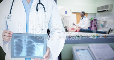 Composite image of doctor looking at xray on tablet