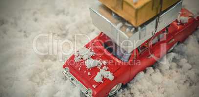 Toy car carrying christmas present on fake snow
