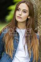 Beautiful Young Woman Leaning Against Tree