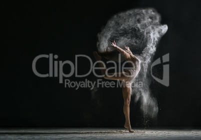 Concept. Flexible girl dancing in cloud of dust