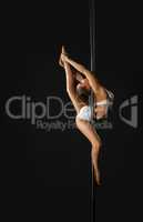 Flexible dancer exercising on pole in studio