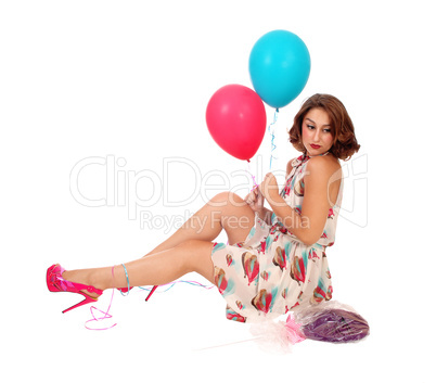 Woman sitting on floor with balloons.