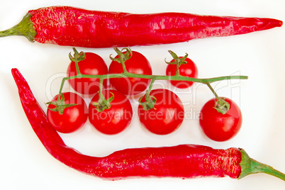 cherry tomatoes and pods of chili peppers isolated