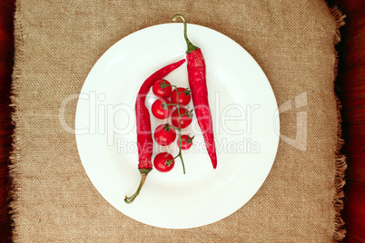 cherry tomatoes and pods of chili peppers on the plate