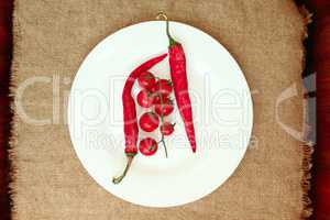 cherry tomatoes and pods of chili peppers on the plate