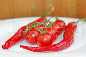 cherry tomatoes and pods of chili peppers on plate