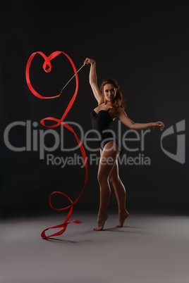 Sexy artistic gymnast dancing with red ribbon